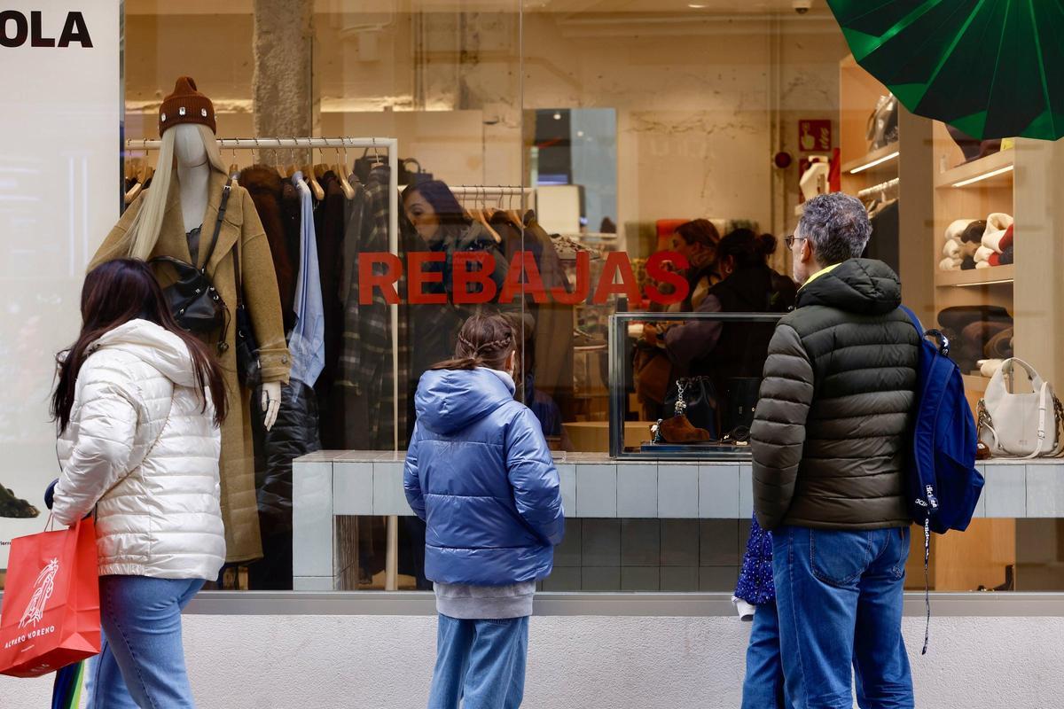 Varias personas observan los escaparates con precios rebajados en una tienda de Córdoba
