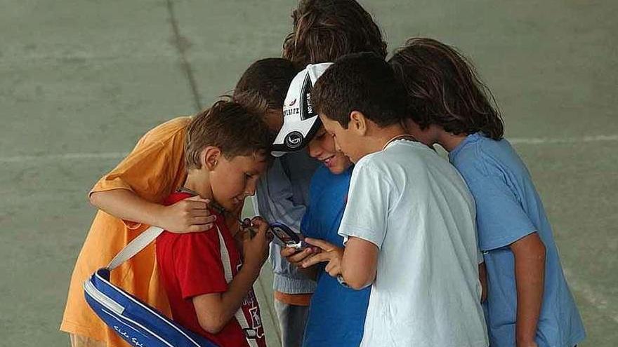 Un grupo de niños miran sus móviles tras hacer deporte.