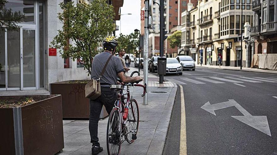 Un hombre camina con la bici de la mano por la ciudad. | Emilio Fraile