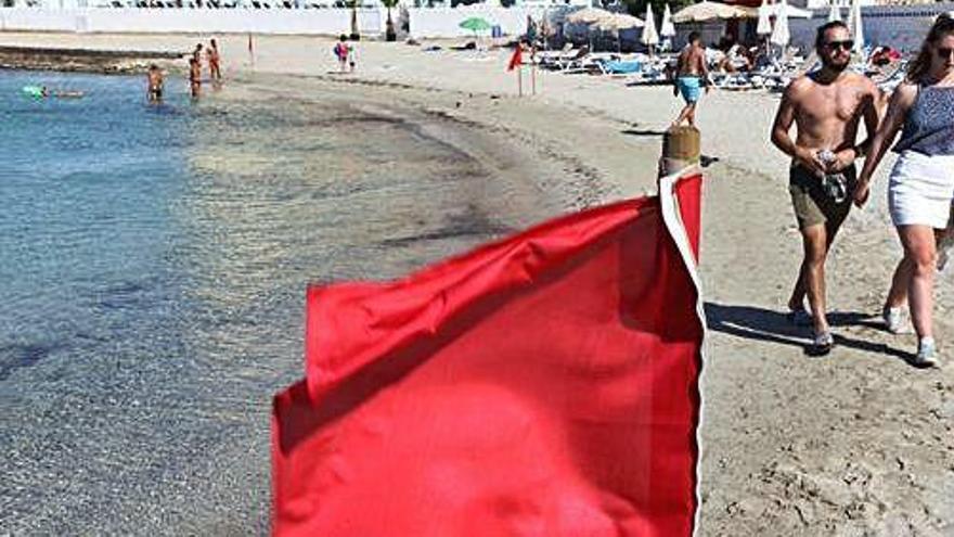 Bandera roja y bañistas en la playa.