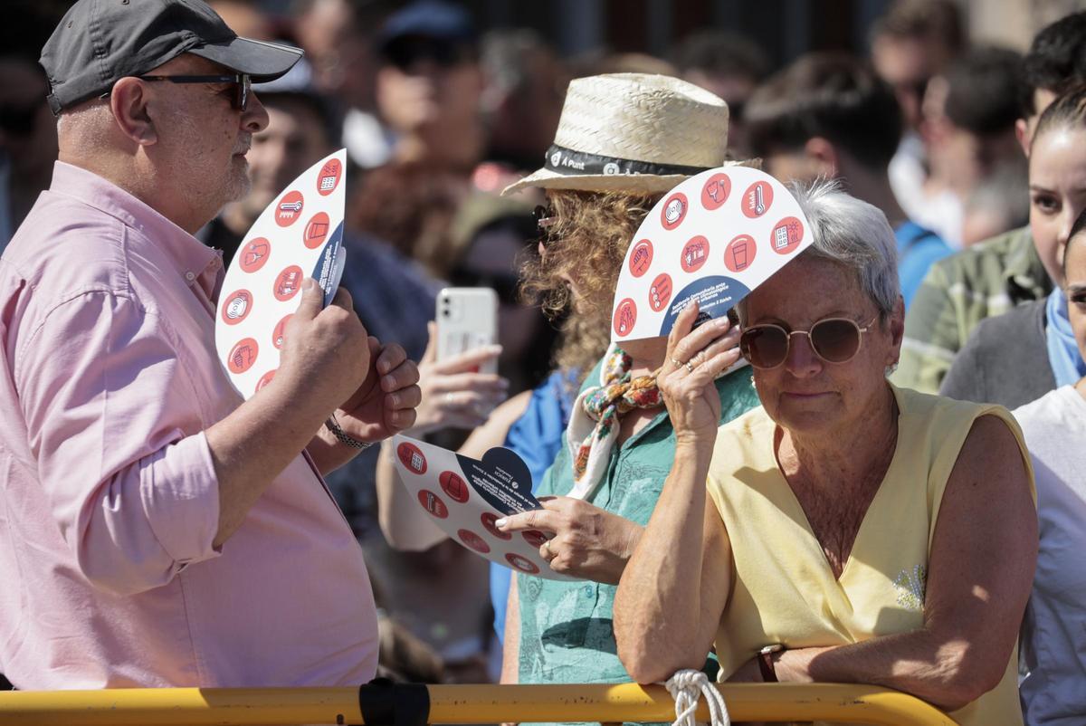 Personas protegiéndose del calor con abanicos y sombreros en las pasadas fallas en València.