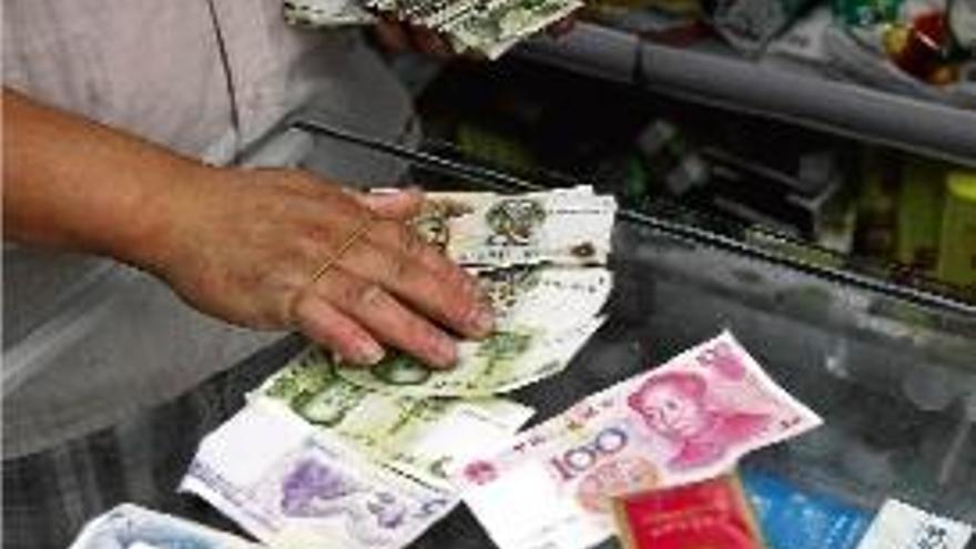 Un comerciant compta bitllets de iuan en una botiga de Pequín.