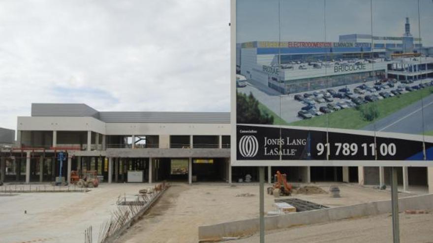 Obras del centro comercial de Iñás, con el cartel que muestra su futuro aspecto a la derecha.