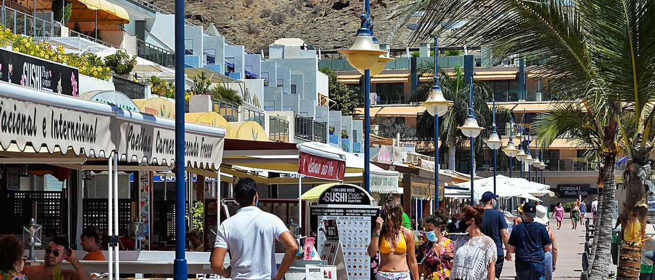 Turistas pasean frente a los bares y restaurantes en Playa de Mogán