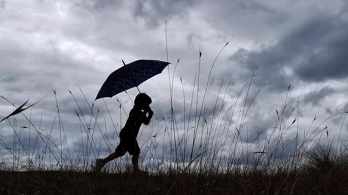 Un niño se resguarda de la lluvia con la ayuda de un paraguas en Mino (A Coruña), el pasado agosto.