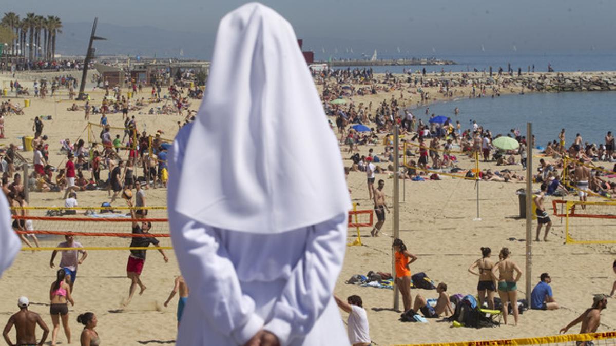 Una monja observa, ayer, la colorida playa de la Nova Icària, donde además de tomar el sol hubo deporte y hasta primeros baños.