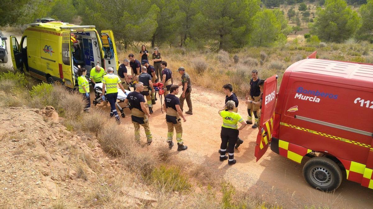 Bomberos y sanitarios mueven al ciclista herido hasta la camilla de la ambulancia.