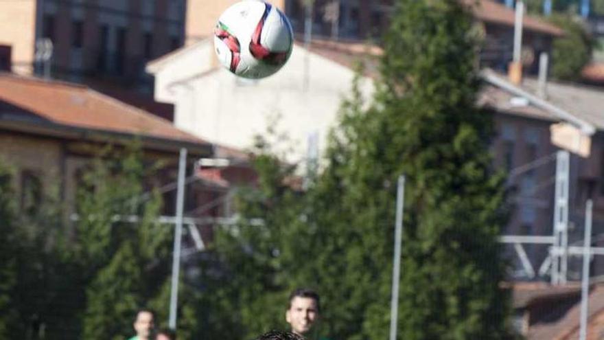 Villa disputa un balón por alto frente a un jugador del Llanes.