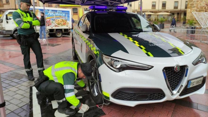 Un agente de la Guardia Civil muestra cómo poner la cadena metálica en una de las ruedas del vehículo. | E. P.