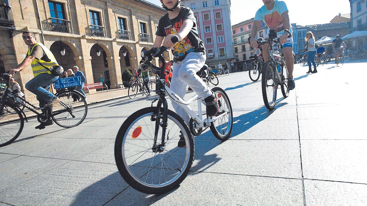 Ciclistas en la plaza de España, al fondo, el edificio Precios Únicos