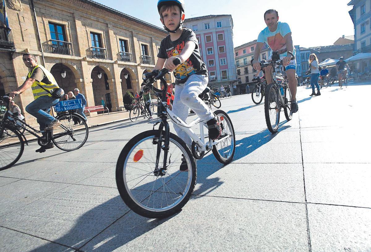 Ciclistas en la plaza de España, al fondo, el edificio Precios Únicos