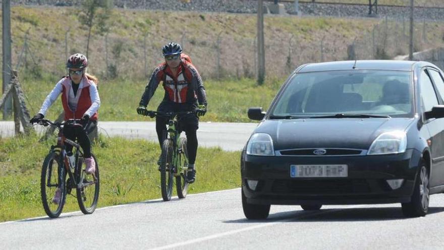 Un coche realiza un adelantamiento a dos ciclistas. // Rafa Vázquez