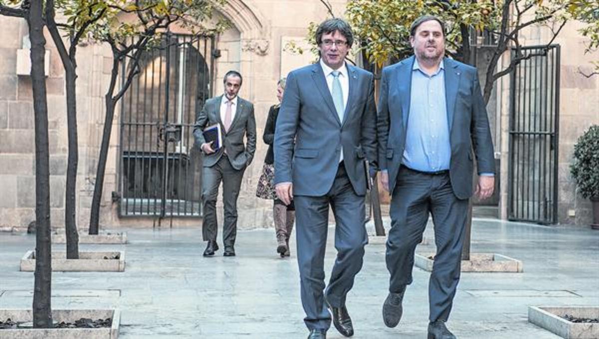 Carles Puigdemont y Oriol Junqueras caminan por el Pati dels Tarongers del Palau de la Generalitat, antes de una reunión de Govern.