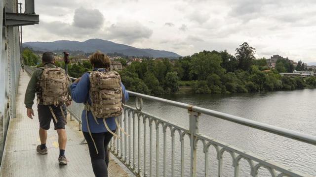Unos peregrinos cruzan el Puente Internacional entre Tui y Valença.