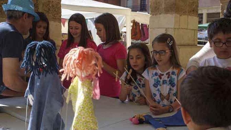 El artesano Antonio Blanco impartiendo a los niños un taller de marionetas en los soportales de la Plaza Mayor.