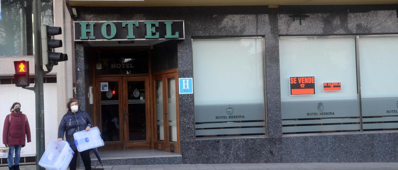 Dos mujeres esperan para cruzar, ayer, junto al Hotel Herbiña, un establecimiento de Cambados que está a la venta