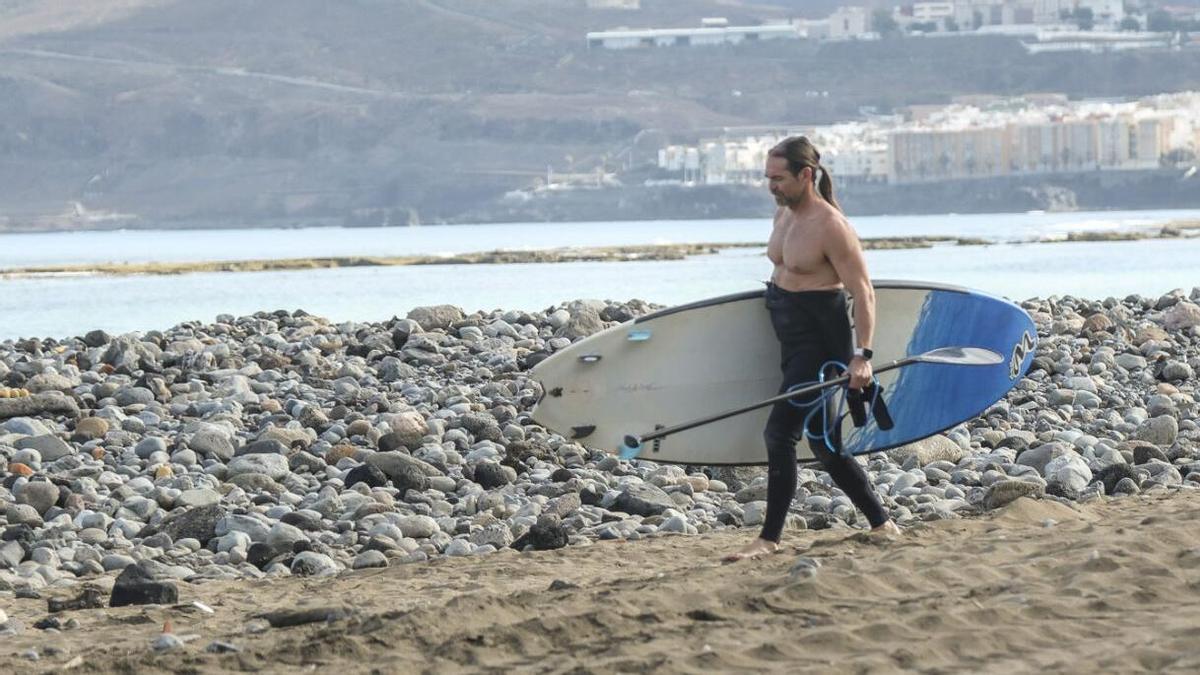 Un surfista camina entre las dunas de callaos en La Cícer.