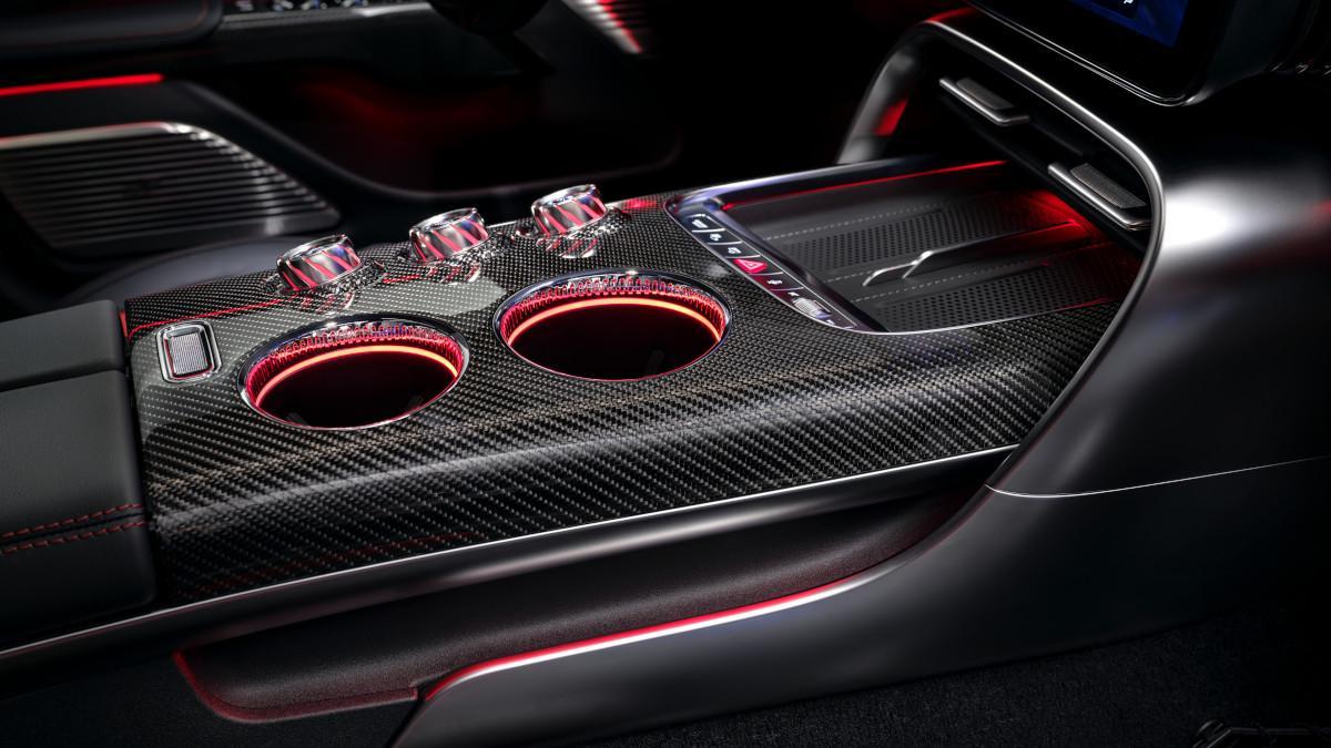 La consola central, revestida en fibra de carbono, incorpora portavasos iluminados y controles físicos que refuerzan la sensación de coche deportivo.