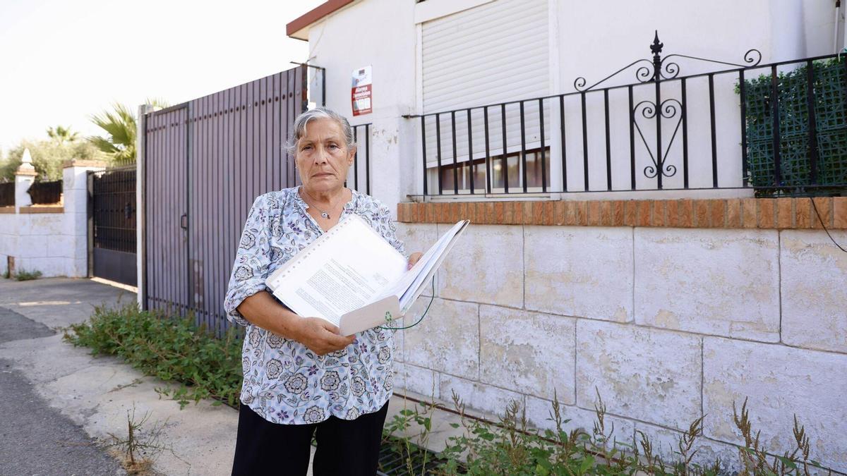 Carmen Guerra sostiene sus documentos frente a su casa.