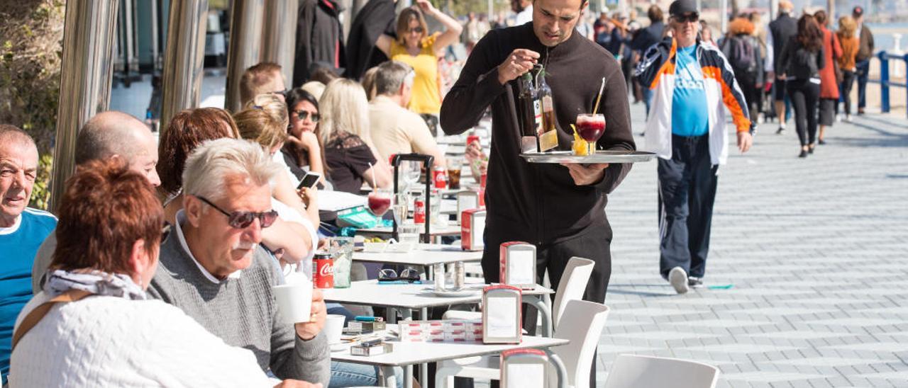 Un camarero trabaja en una terraza en el Passeig de Gomiz.