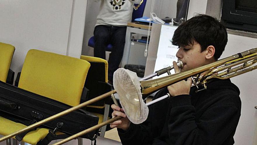 Un alumno con un trombón con mascarilla.