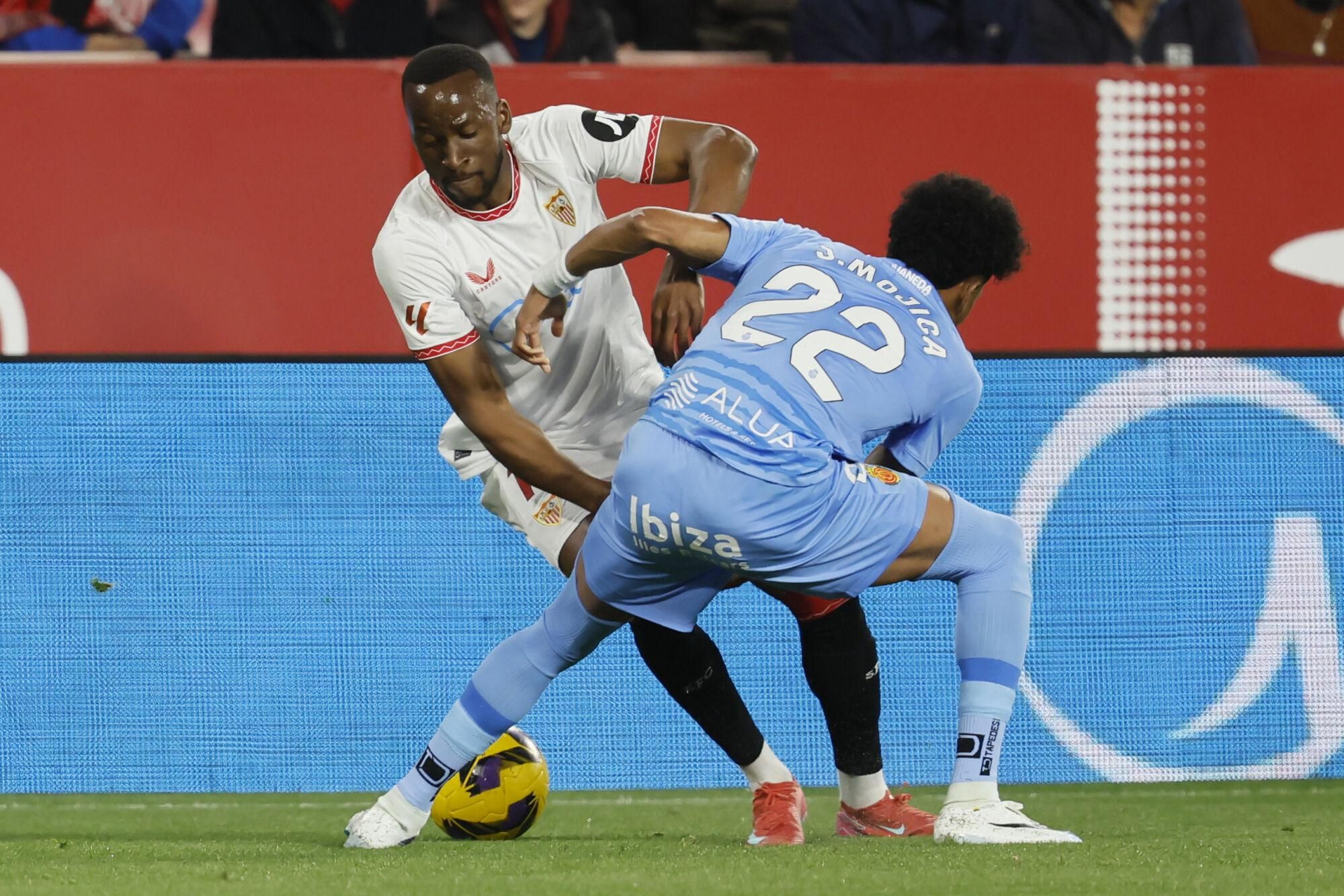 El delantero del Sevilla Dodi Lukébakio (i) trata de escapar de Johan Mojica, del Mallorca, durante el partido de LaLiga de fútbol que Sevilla FC y RCD Mallorca disputan en el estadio Ramón Sánchez-Pizjuán. EFE/José Manuel Vidal. (Sevilla) (Mallorca)