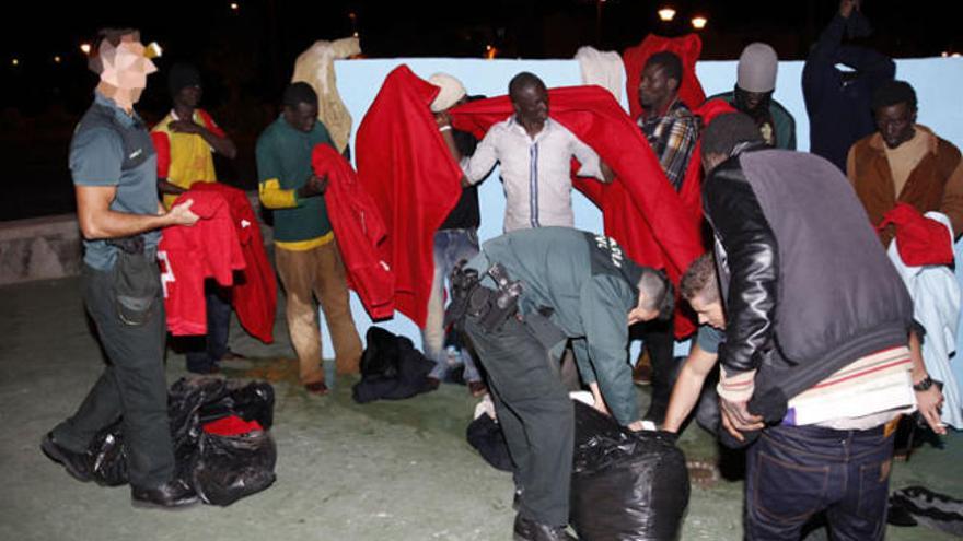 Varios de los inmigrantes que llegaron en la patera se cubren del frío con mantas de la Cruz Roja. | domingo martín