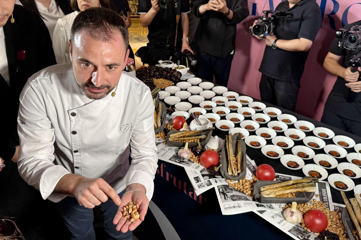 El xef del Disfrutar Eduard Xartuch ensenya alguns dels ingredients amb què es fa la salsa de calçots a un grup de ciutadans xinesos.