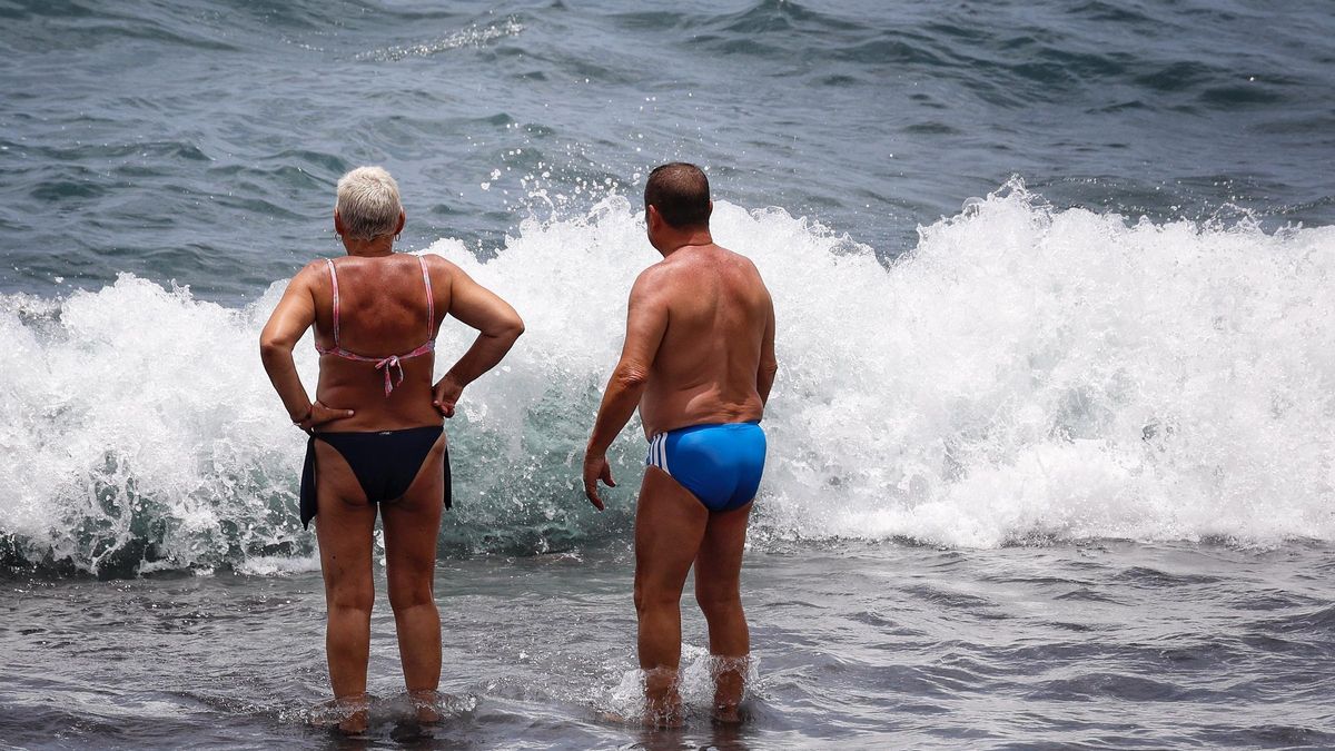 Dos personas se refrescan en el mar durante esta una jornada de esta ola de calor.
