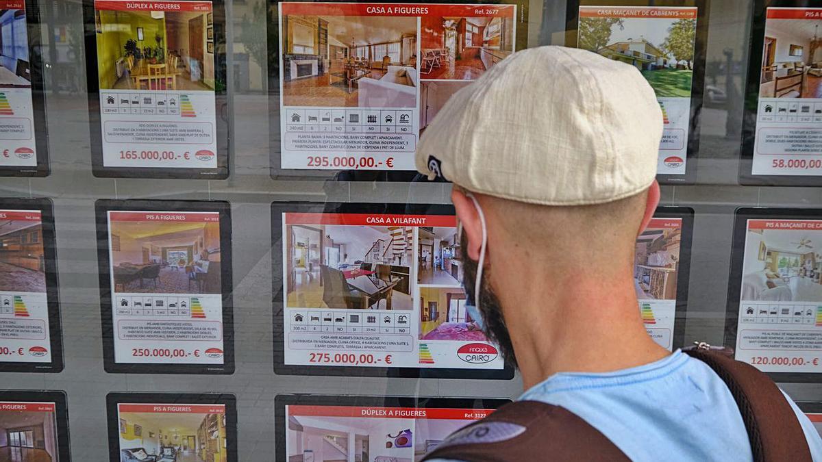 Un jove observa anuncis de cases a la venda en una immobiliària | BORJA BALSERA