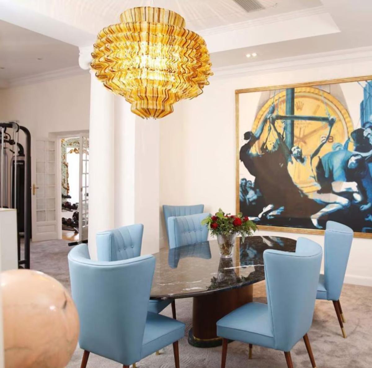 El comedor está decorado con sillones clásicos en azul celeste, una mesa de mármol negro y una lámpara contemporánea