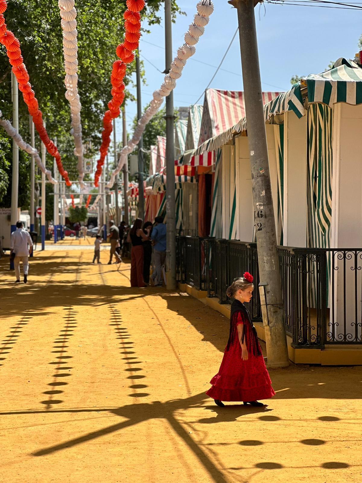 Una niña pasea junto a su familia por el Real vestida de flamenca durante el fin de semana de preferia.
