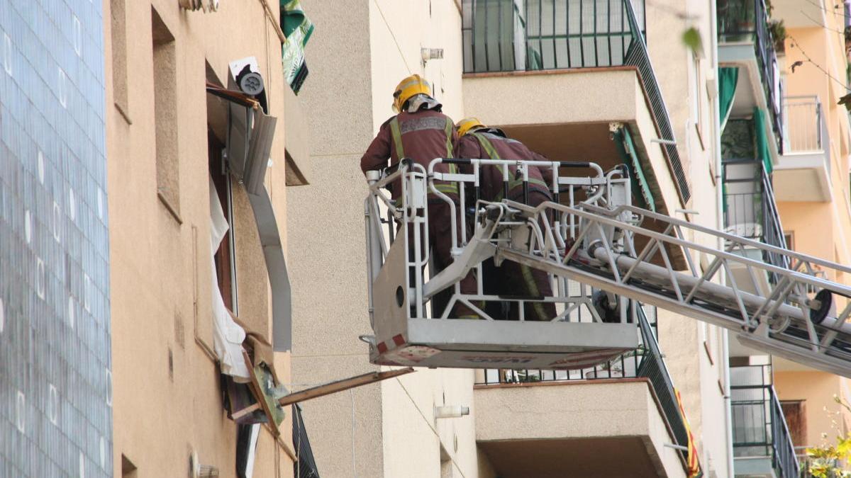 Dos bombers en una grua elevadora entrant per una finestra.