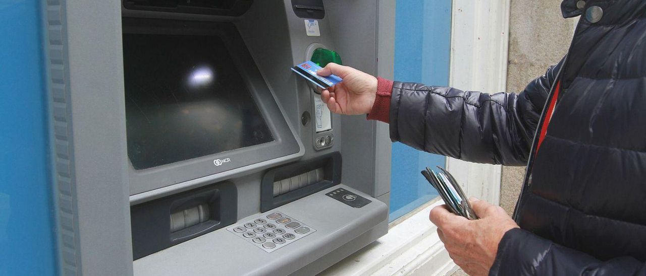 Un cliente de un banco usa su tarjeta en un cajero automático en Ourense.