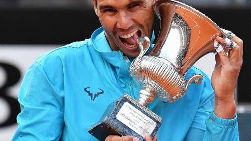 Nadal muerde el trofeo tras imponerse a Djokovic. // Efe