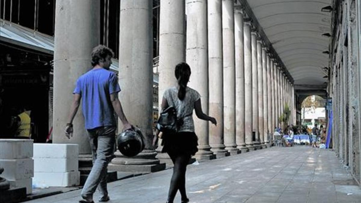 Una pareja pasea, ayer, por el pasadizo porticado del mercado de la Boqueria que el ayuntamiento planea cerrar por las noches.