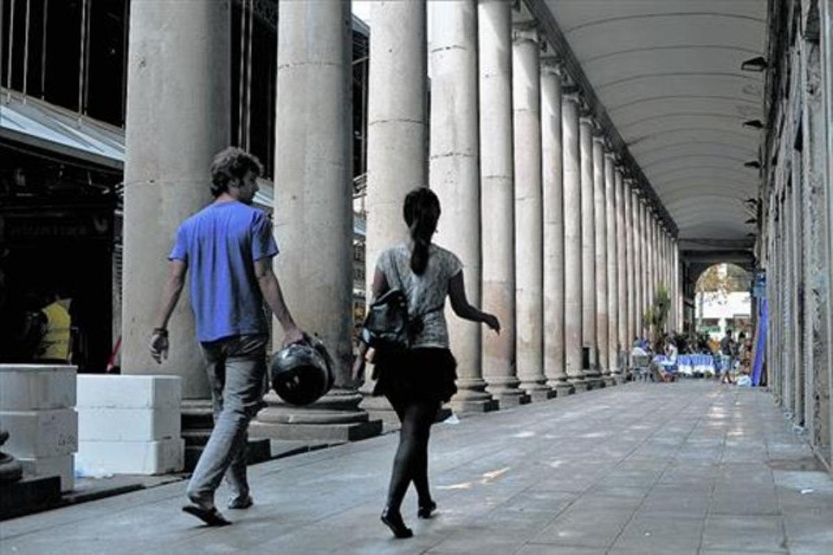 Una parella passeja, ahir, pel passadís porticat del mercat de la Boqueria que l’ajuntament planeja tancar a les nits.