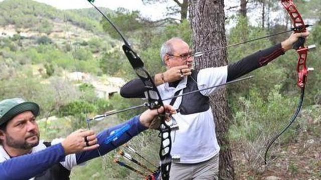 Dos arqueros apuntan sus flechas con atención contra uno de los blancos 3D.