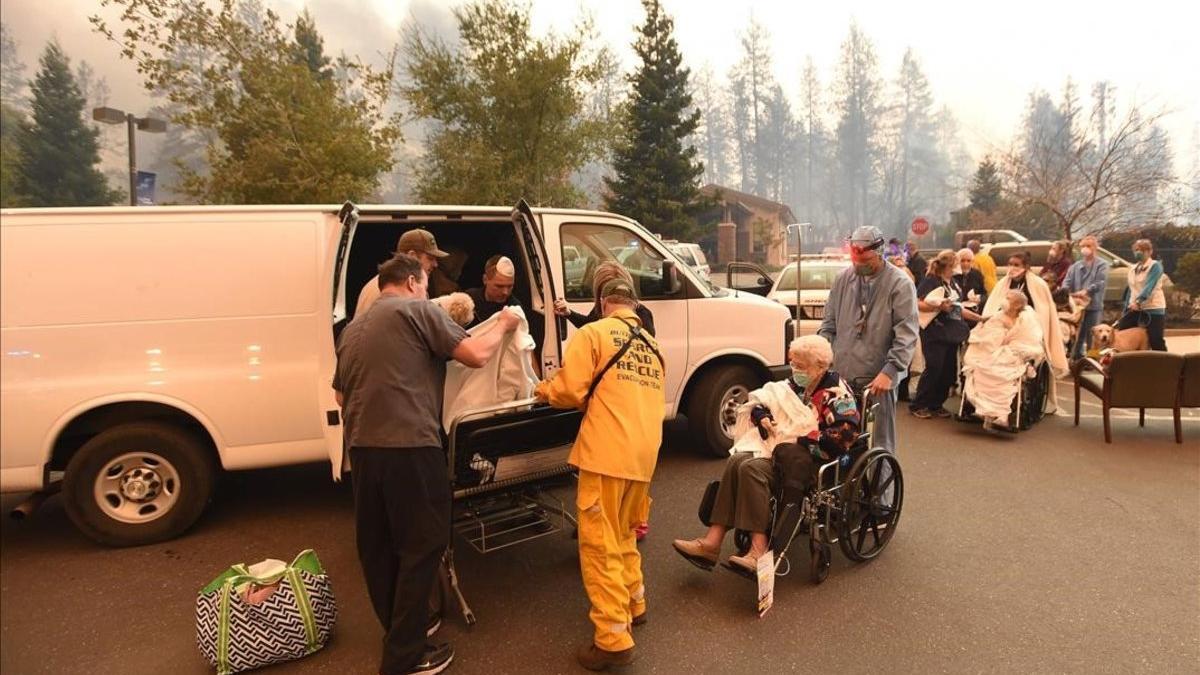 Miembros de los servicios de rescate trasladan a un grupo de personas lejos de los efectos de las llamas, en la localidad californiana de Paradise.