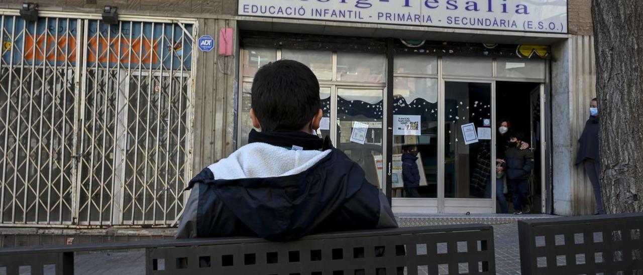 Eric, de espaldas, frente al colegio Roig Tesalia de Barcelona, que cierra este curso.