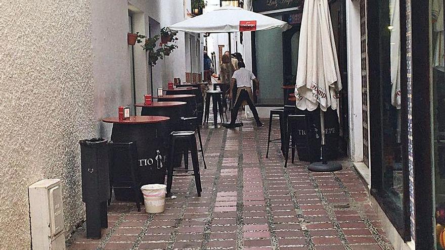 Un camarero recoge una sombrilla en una terraza.