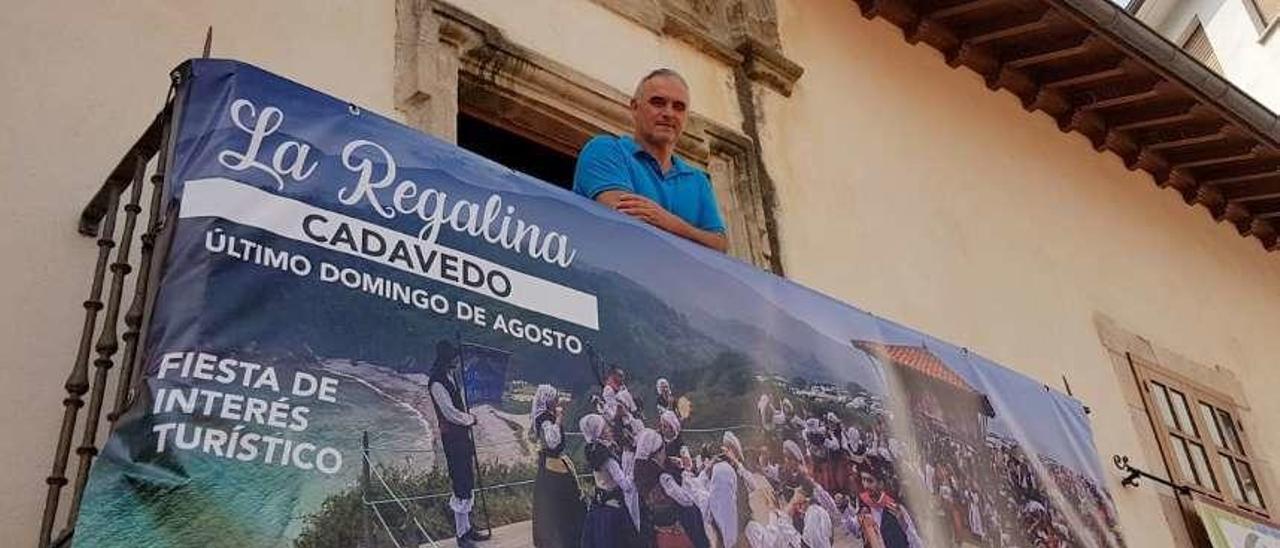 Xosé Manuel Fernández, asomado a un balcón del que cuelga un cartel de La Regalina, en Luarca.