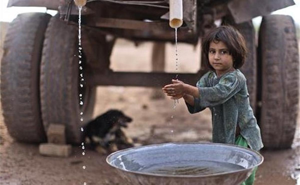 Una nena pakistanesa es renta les mans amb l’aigua d’un camió cisterna en una fàbrica de totxos als afores d’Islamabad (Pakistan).