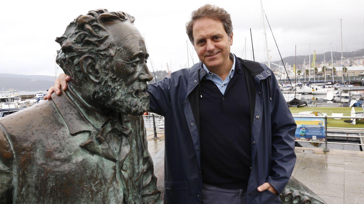 O escritor Domingo Villar a carón dun monumento a Julio Verne.