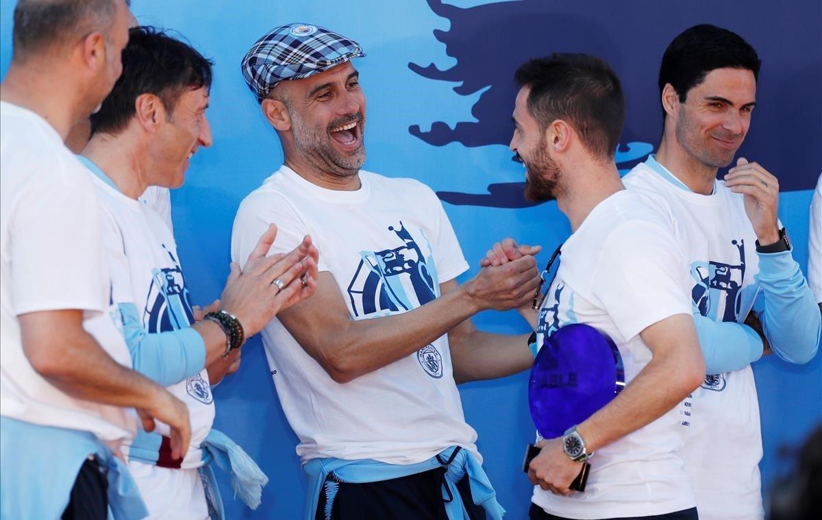 El entrenador del Manchester City , Pep Guardiola, conversa con Bernardo Silva durante la celebración de todos los títulos a nivel nacional en Manchester (Reino Unido). El Manchester City ha ganado esta temporada la liga inglesa, la FA Cup, la Copa de la Liga y la Community Shield. 