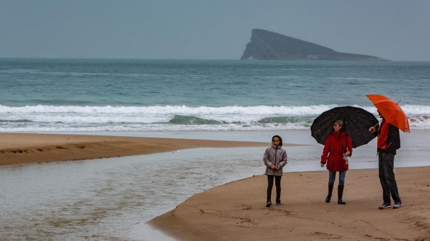 Turistas observan la acción de las fuertes lluvias sobre la arena de Levante.