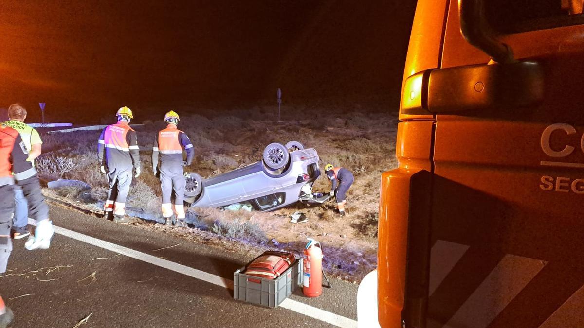 Los bomberos, junto al coche volcado en Teguise este jueves.