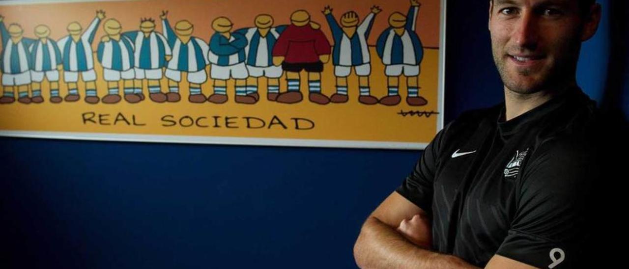 El delantero Imanol Agirretxe posa junto a un cartel de la Real Sociedad.