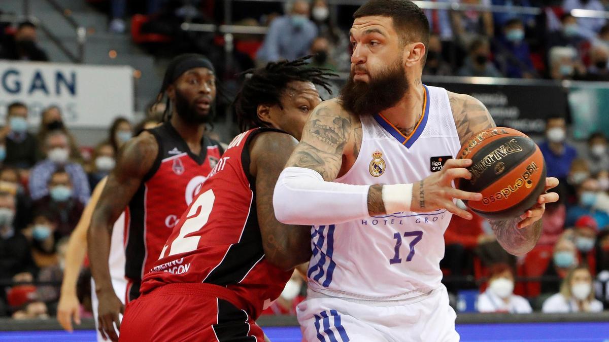 El pívot del Real Madrid Vincent Poirier (d) juega un balón ante Evan Mobley, del Casademont Zaragoza.