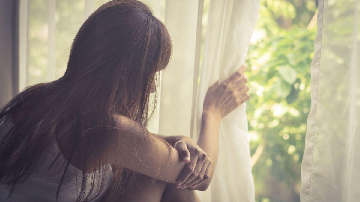 Una mujer mira por una ventana.